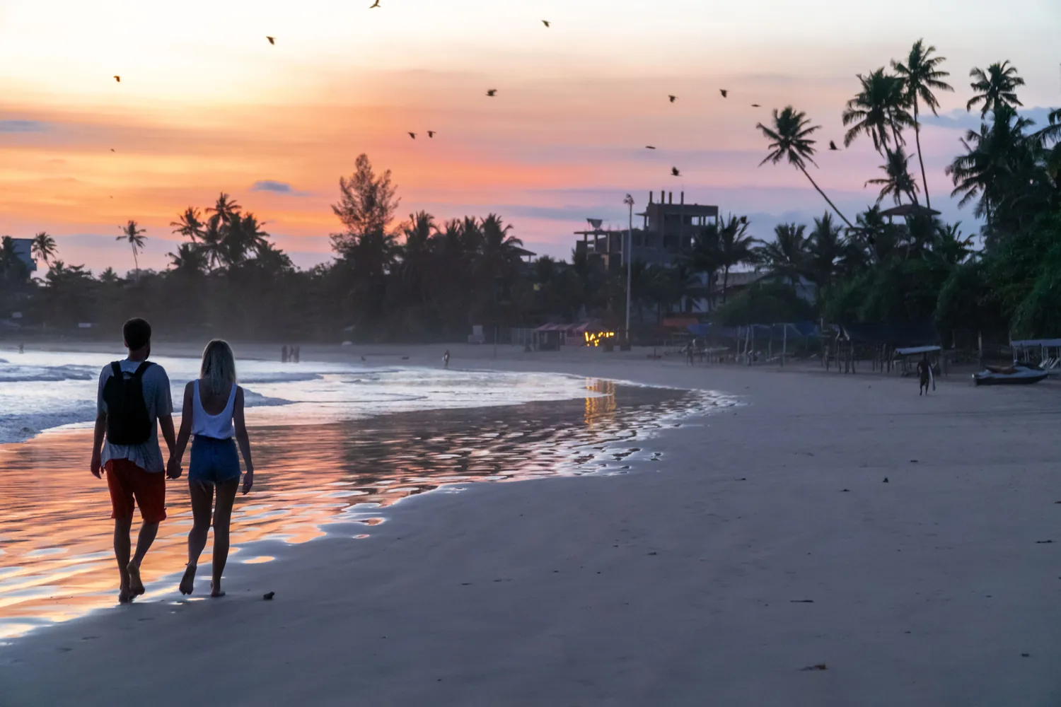 Couple walking along a Sri Lankan beach at sunset