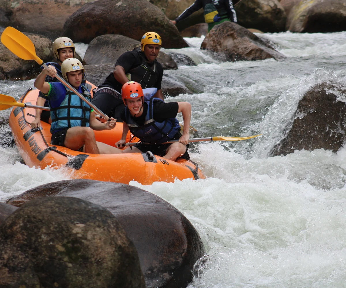 Travellers white-water rafting through rocky rapids