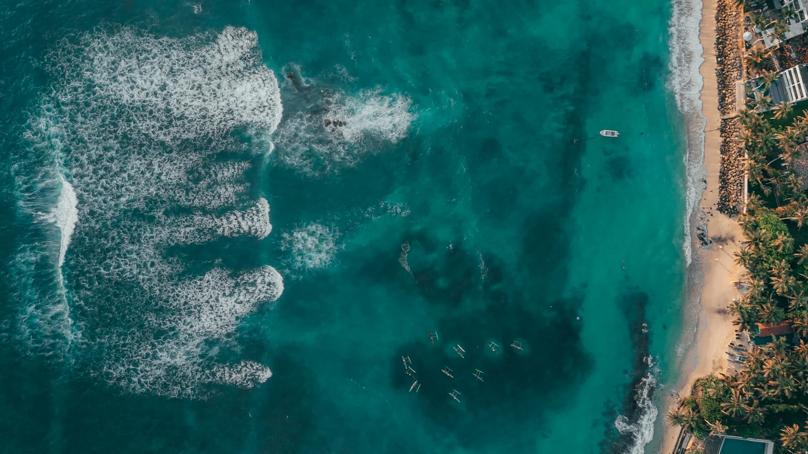 Aerial view of turquoise water, surf and a palm-lined beach on Sri Lanka's south coast