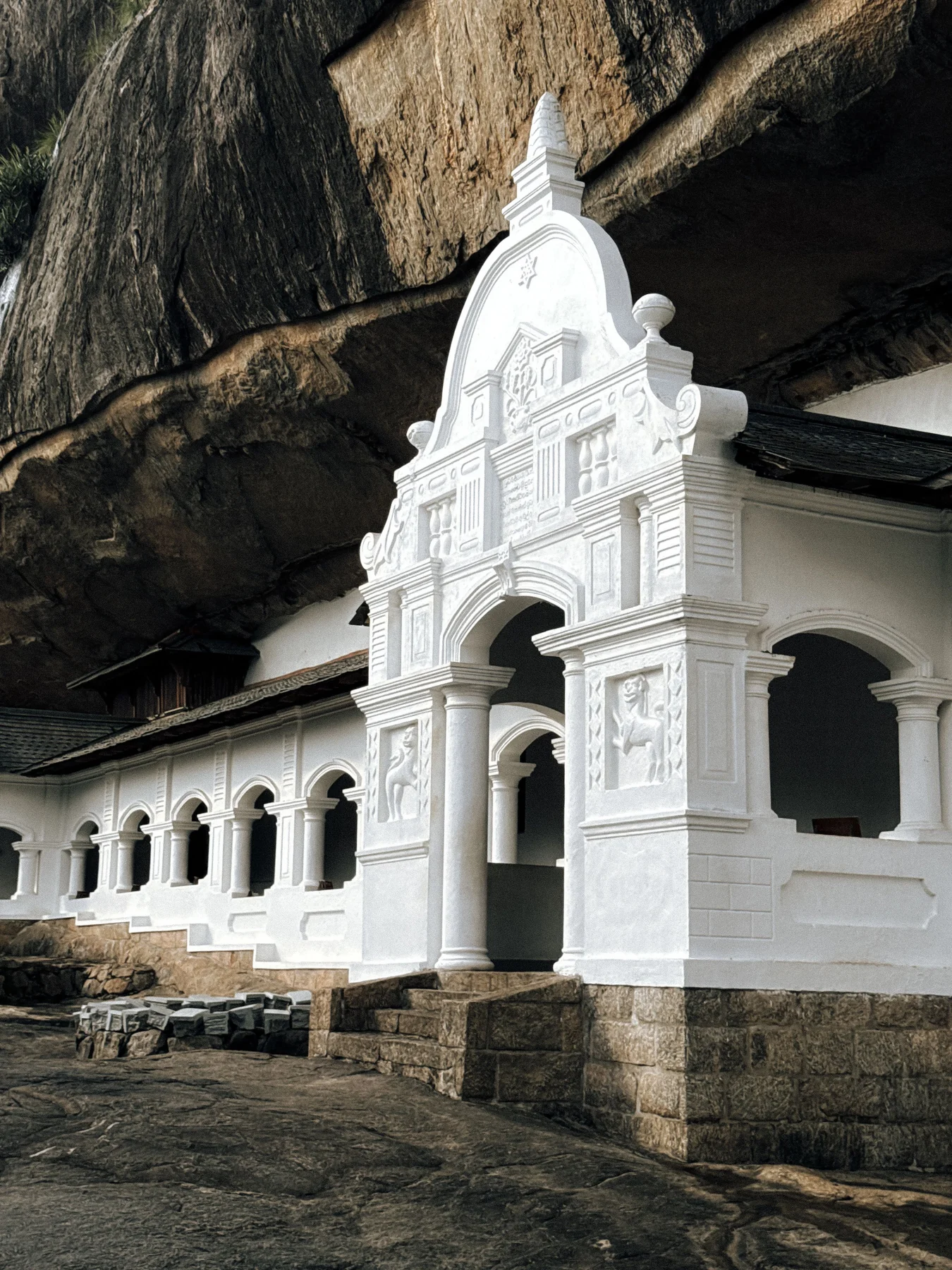 White temple entrance beneath the rock overhang at Dambulla